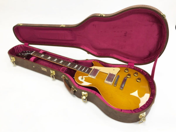 Electric guitar with honey burst finish in brown hard shell case with red interior lining on white background