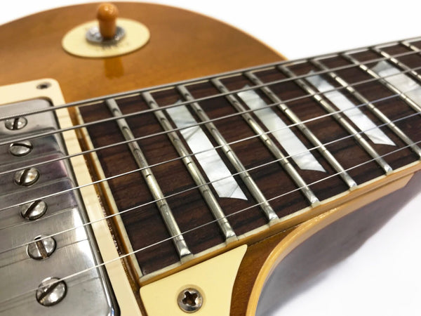 Close-up of electric guitar fretboard with mother of pearl inlays, metal frets, and strings on a sunburst finish body from Coffee House Guitars.
