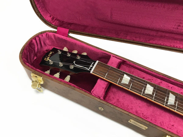 Gibson guitar headstock and neck with pearl inlays in pink velvet-lined hard case with gold latches