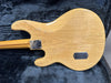 Vintage natural finish electric guitar body showing wood grain and wear, resting on dark gray plush guitar case lining