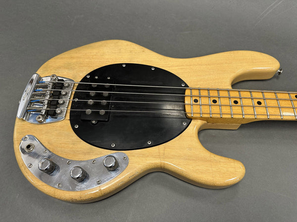 Vintage natural finish electric bass guitar with black pickguard and chrome control knobs on gray background