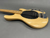 Natural finish electric bass guitar with black pickguard and chrome bridge hardware on gray background