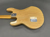 Back of natural wood electric guitar body showing neck plate and control cavity cover on gray background