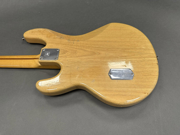 Back of natural wood electric guitar body showing neck plate and control cavity cover on gray background