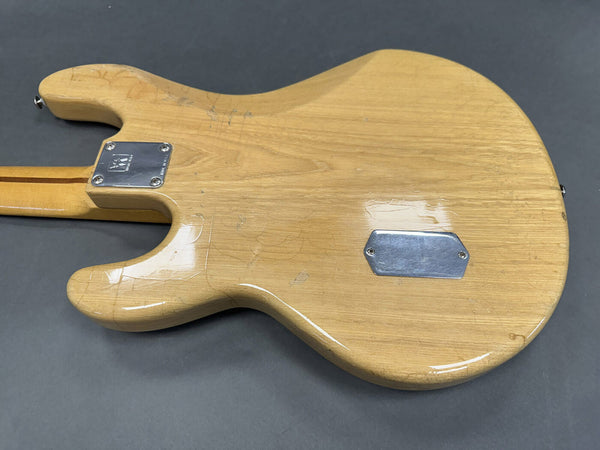 Back of natural wood finish electric guitar body showing neck joint plate and rear cavity cover on gray background