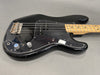 Black electric bass guitar with maple neck and two control knobs on gray background