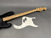 Black Greco Mercury Bass guitar with maple neck and frets next to a white pickguard on gray background