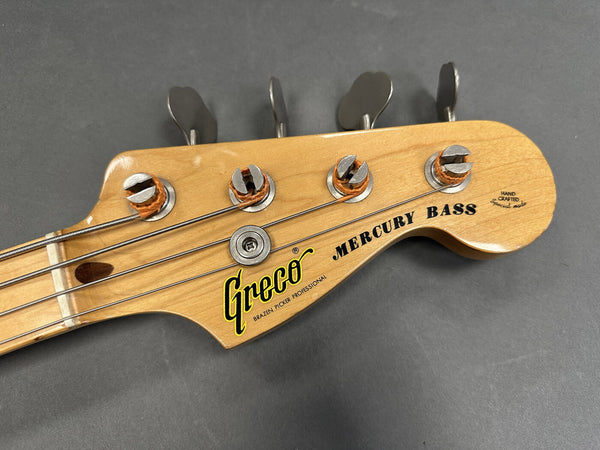 Close-up of Greco Mercury Bass guitar headstock with tuning pegs and natural wood finish on gray background