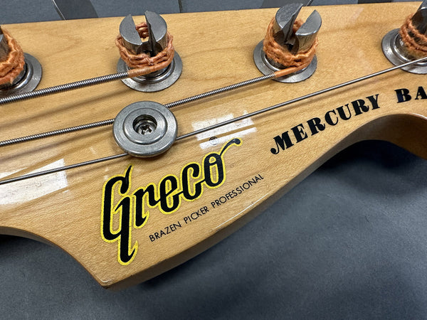 Close-up of Greco Mercury Bass guitar headstock showing tuning pegs, strings, and logo with "Brazen Picker Professional" text on natural wood finish.