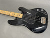 Black electric bass guitar with maple neck and black pickguard on gray background, vintage style with two control knobs and four strings