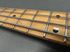 Close-up of maple guitar neck fretboard with four metal strings and black dot inlays on a gray background