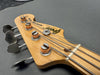 Close-up of Gresco Mercury Bass electric bass guitar headstock with four tuning pegs on gray surface