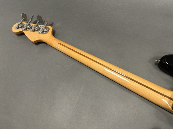 Back of maple guitar neck with four tuning pegs and skunk stripe on gray background