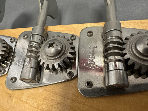 Close-up view of Greco brand vintage guitar tuning pegs with metal gears and screws on a natural wood headstock