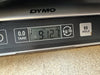 Close-up of DYMO digital scale displaying guitar weight of 9 pounds 12.7 ounces with tare and hold buttons visible