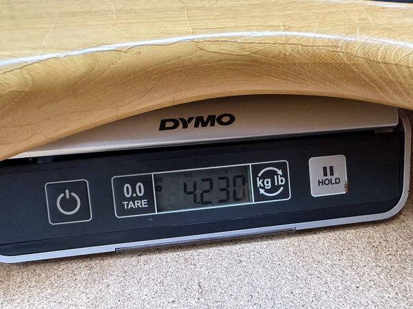 Close-up of a guitar body on a Dymo digital scale showing weight of 4.230 kilograms, highlighting guitar weight measurement for Coffee House Guitars product listing.