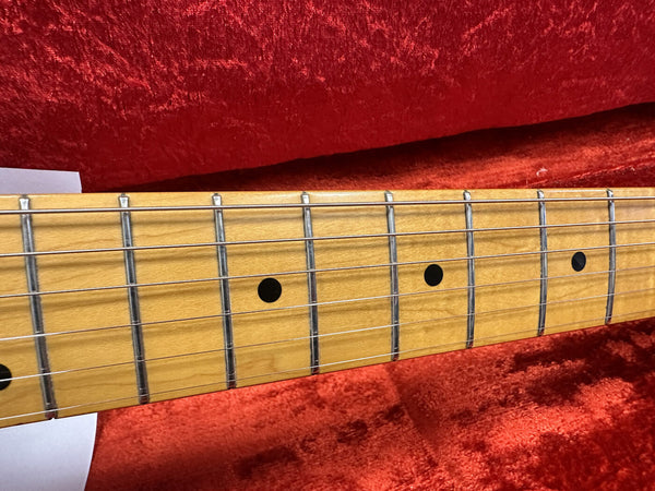 Close-up of maple guitar fretboard with metal frets and black dot inlays against red velvet background