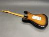 Sunburst finish electric guitar viewed from the back showing maple neck and tuning pegs on grey background