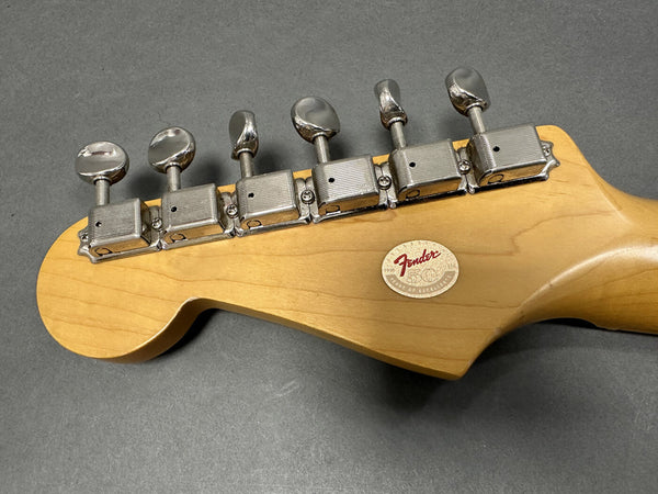 Back of Fender guitar headstock showing vintage-style tuning pegs and 50th anniversary decal on maple wood finish