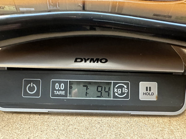 Digital scale displaying weight 7 pounds 9.4 ounces with DYMO branding for Coffee House Guitars product listing weight verification.