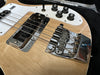 Close-up detail of natural wood electric bass guitar body showing chrome bridge, black pickup, white pickguard, and black tone and volume control knobs