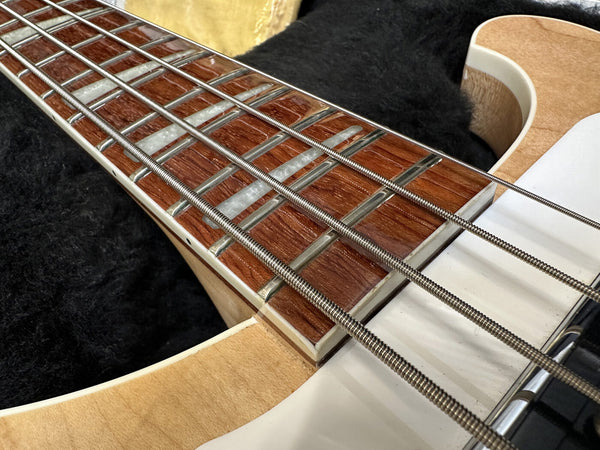 Close-up of electric bass guitar rosewood fretboard with pearl block inlays and steel strings on natural wood neck