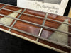 Close-up of bass guitar fretboard with triangular pearl inlays and thick metal strings on wooden neck