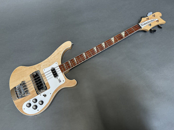 Rickenbacker electric bass guitar with natural wood finish, white pickguard, and distinctive triangle inlays on rosewood fretboard on gray background
