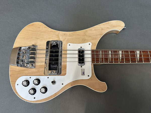 Natural finish electric bass guitar with chrome hardware, white pickguard, and rosewood fretboard on gray background