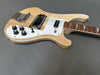Electric bass guitar with natural wood finish, white pickguard, and chrome hardware on gray background.