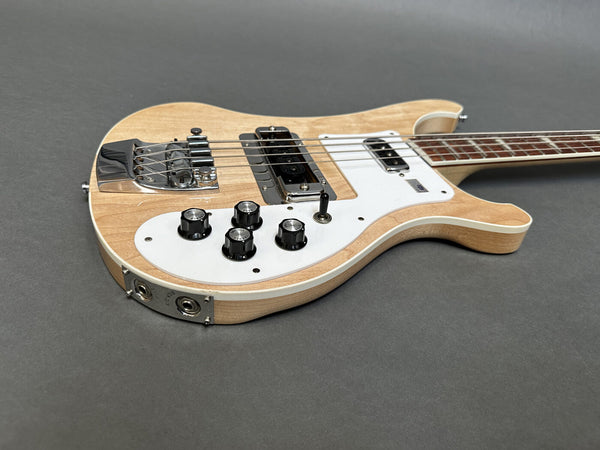 Natural wood finish electric bass guitar with white pickguard, chrome bridge, four control knobs, and two pickups on gray background