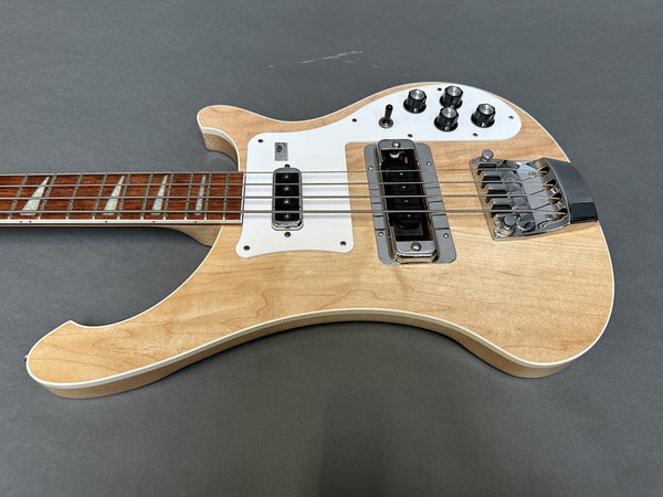 Natural finish electric bass guitar with white pickguard, chrome bridge, four control knobs, toggle switch, and rosewood fretboard