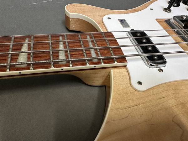 Close-up of maple body and rosewood fretboard with white trapezoid inlays on electric guitar from Coffee House Guitars, showing strings and pickups on gray background
