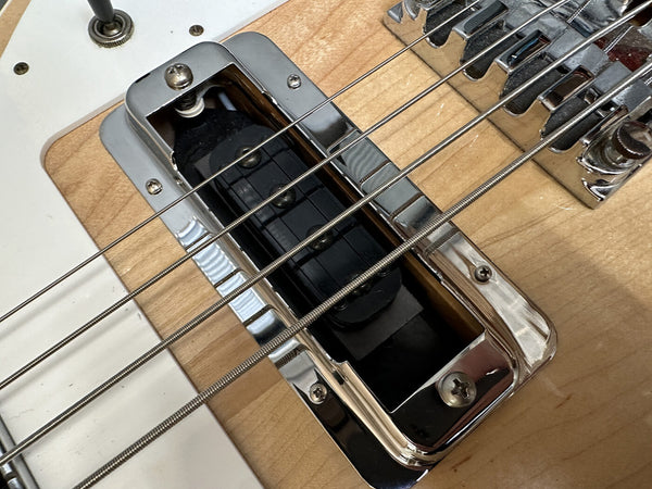 Close-up of electric guitar pickup and bridge with chrome hardware on natural wood finish body