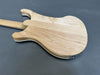 Back of natural wood electric guitar body with smooth, glossy finish on dark gray background