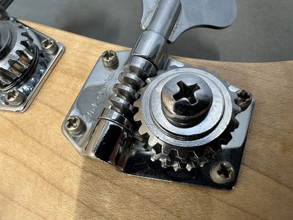 Close-up of metal tuning machine gear and screw on natural wood electric guitar headstock at Coffee House Guitars