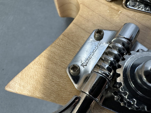 Close-up of Rickenbacker guitar tuning peg on natural wood headstock showing metal machine head and screws