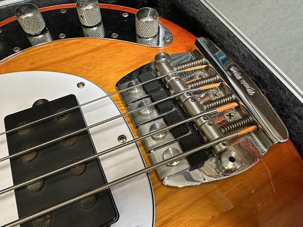 Close-up of Rickenbacker bass guitar bridge and pickup with sunburst finish and chrome hardware in guitar case