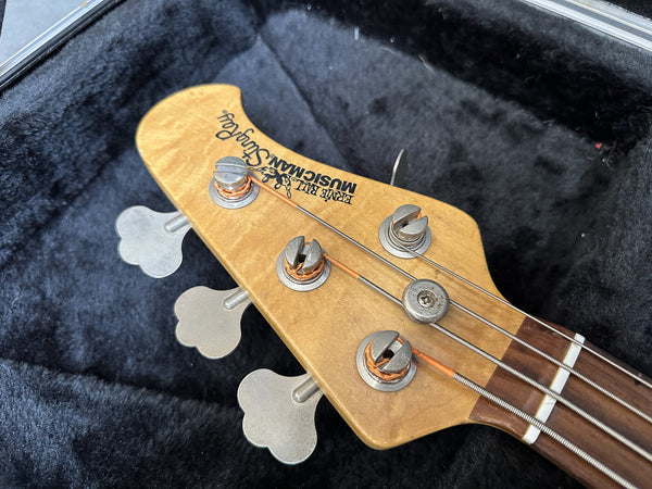 Ernie Ball Music Man Stingray bass guitar headstock with tuning pegs and strings close-up in case interior