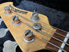 Closer view of vintage electric bass guitar headstock with metal tuning pegs and steel strings in black case interior