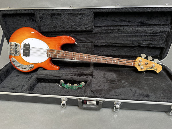 Ernie Ball Music Man StingRay electric bass guitar with honey burst finish in black plush-lined hard case with detached circuit board.