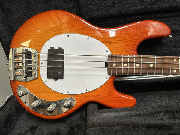 Vintage orange sunburst electric bass guitar with white pickguard and chrome control knobs in black plush case