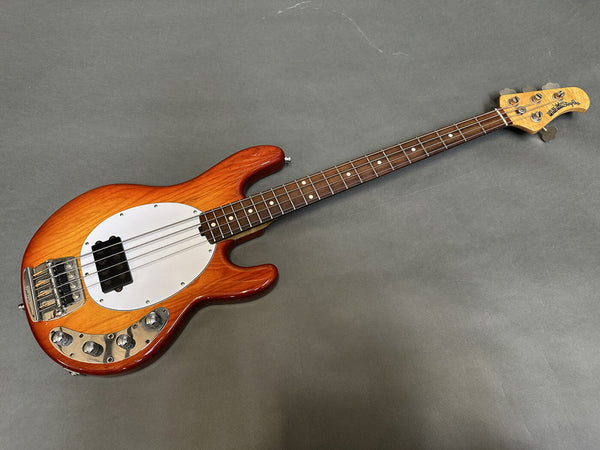 Sunburst Music Man StingRay electric bass guitar with white pickguard and rosewood fretboard on gray background
