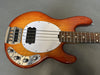 Electric bass guitar with sunburst finish, white pickguard, and chrome control knobs on gray background