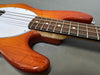 Close-up of electric bass guitar body and fretboard with sunburst finish and white pickguard on gray background