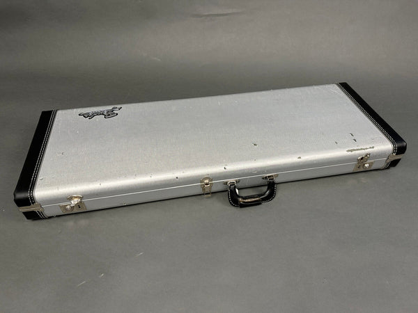 Silver vintage Fender guitar hard case with black leather corners and handle on gray background