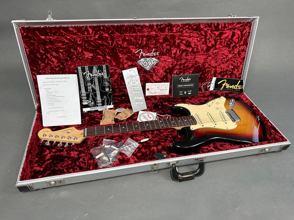 Fender Stratocaster electric guitar in sunburst finish with original case, manuals, registration card, and accessories displayed on red velvet interior lining for sale at Coffee House Guitars