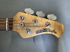 Ernie Ball Music Man StingRay bass guitar headstock with tuning pegs and strings on gray background