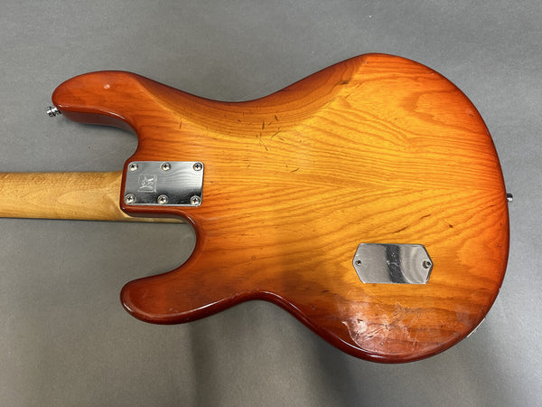 Back of vintage electric guitar with sunburst finish and metal neck plate on gray background