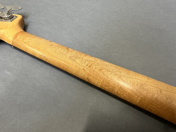 Close-up image of smooth natural wood guitar neck and headstock on gray surface showing wood grain texture
